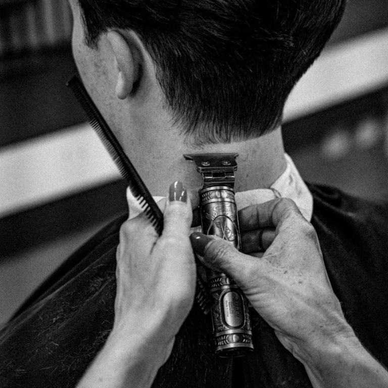 Nahaufnahme einer Hand, die einen Haarschnitt mit einer elektrischen Maschine durchführt.